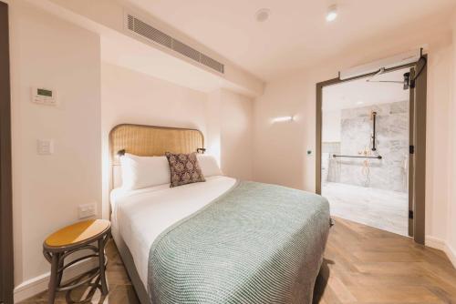1 dormitorio con cama, taburete y ducha en The Sarah by Urban Rest en Sídney