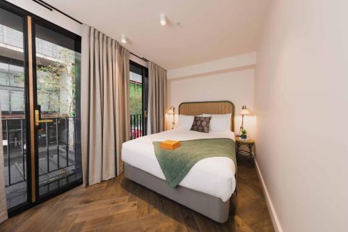 a bedroom with a bed and a large window at The Sarah by Urban Rest in Sydney