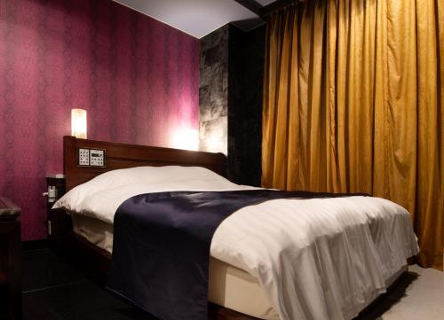 una camera con un letto in una stanza con pareti rosa di HOTEL ZERO a Tatsuno