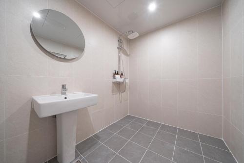 a white bathroom with a sink and a mirror at Aank Hotel Cheonan Station 1st in Cheonan