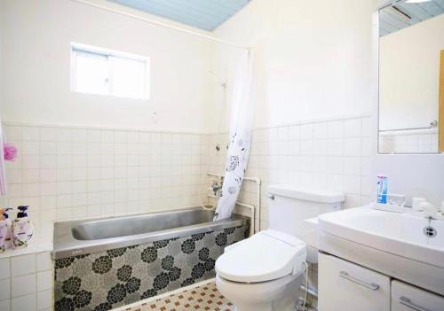 a bathroom with a toilet and a sink and a tub at Happy House in Kadena