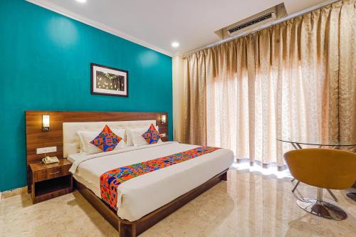 a bedroom with a large bed and a blue wall at FabHotel Chris in Bangalore