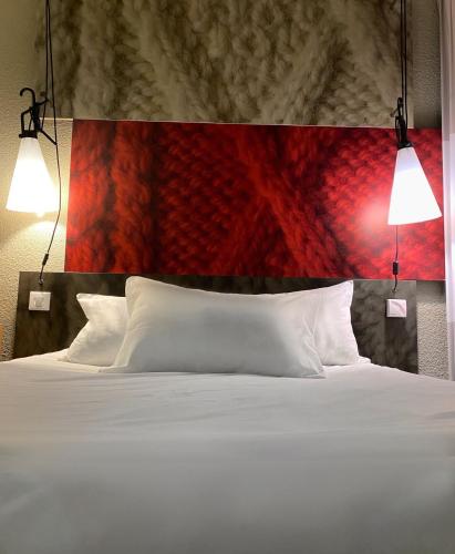 a bedroom with a white bed with two lights above it at ibis Saint-Omer Centre in Saint-Omer