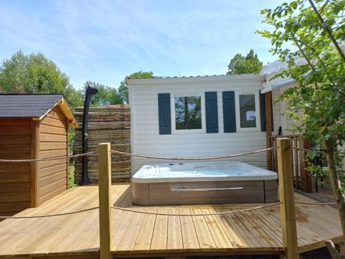 una terraza de madera con bañera de hidromasaje en una casa en Le Mill, en Meilhan