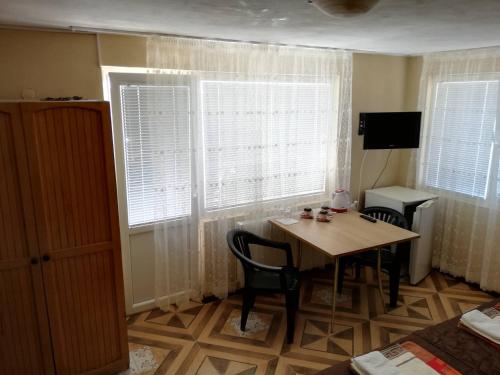 een kamer met een tafel, 2 stoelen en ramen bij Guest House Dimi in Byala