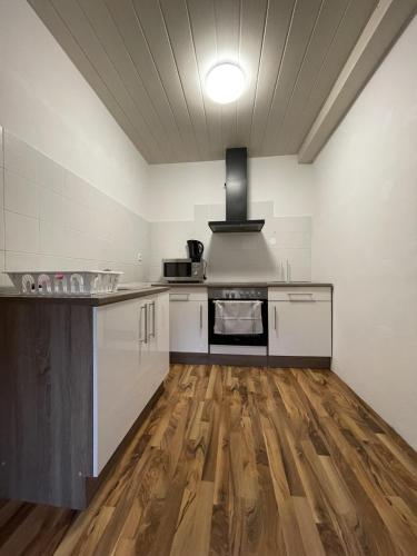 cocina con armarios blancos y suelo de madera en Monteurapartment - Messeapartment bis zu 3 Personen, en Hannover