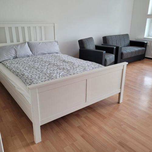 a white bed in a room with two chairs at Ludwigsturm Appartement in Straubing in Straubing
