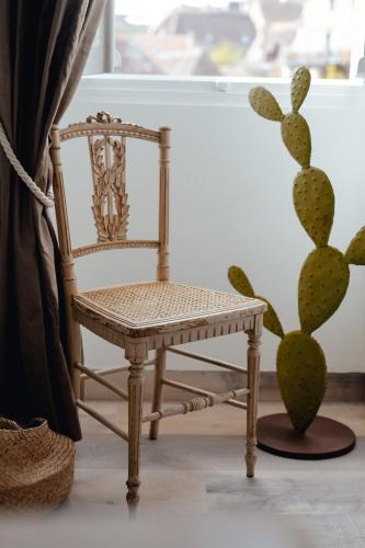 a chair in front of a window next to a cactus at Hôtel l'Abbaye in Saint-Cyprien