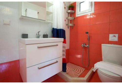 a red bathroom with a sink and a toilet at Aelia House - Helios in Lefkada Town