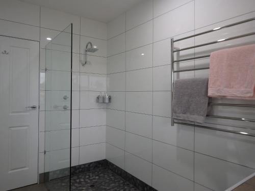 a white bathroom with a shower and a towel at Blue Wren Studio Apartment in Currency Creek