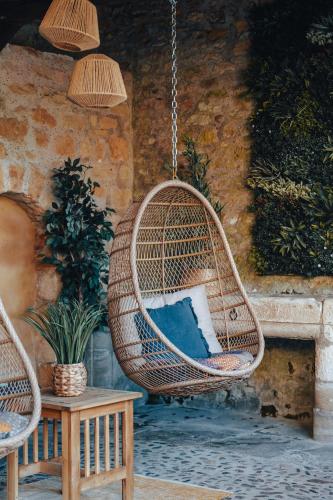 a hanging rattan chair with a pillow on a patio at Hôtel l'Abbaye in Saint-Cyprien