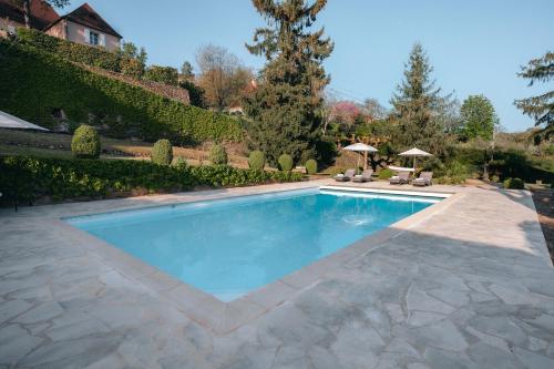 a swimming pool with blue water in a yard at Hôtel l'Abbaye in Saint-Cyprien