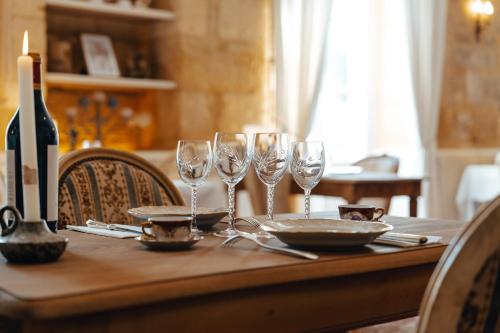 a table with wine glasses and a bottle of wine at Hôtel l'Abbaye in Saint-Cyprien
