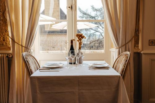 a table with wine glasses and a window at Hôtel l'Abbaye in Saint-Cyprien