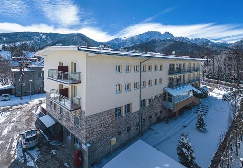 an apartment building in the snow with mountains in the background at Wanta in Zakopane