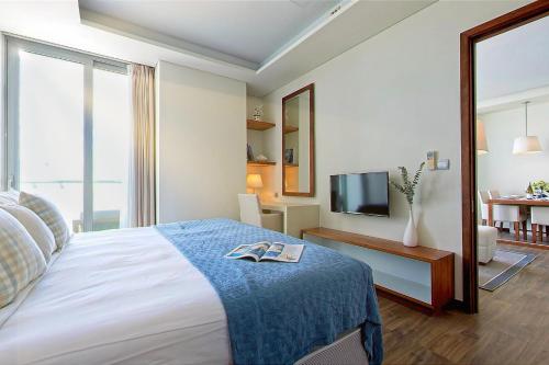 a hotel room with a bed and a television at Stunning Apartments Across My Khe Beach ! Rooftop Pool & Gym in Da Nang