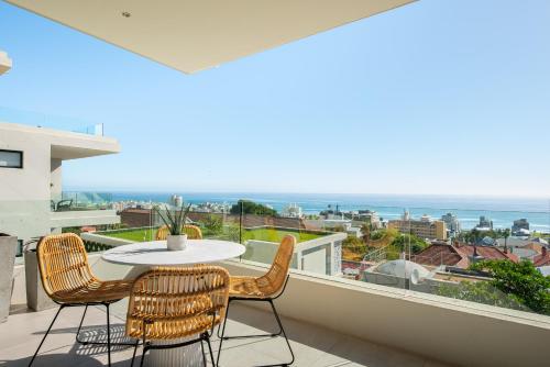 einen Balkon mit einem Tisch, Stühlen und Meerblick in der Unterkunft The Marlo Luxury Suites by Totalstay in Kapstadt