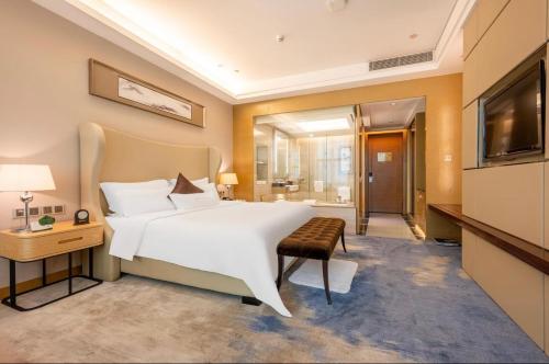 1 dormitorio con 1 cama blanca grande y TV en Shenzhen Shuidu Holiday Hotel, North Railway Station, en Shenzhen