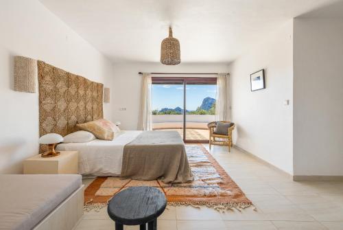 a bedroom with a bed and a couch and a window at UNIO Ibiza - Adults Only in Cala Vadella