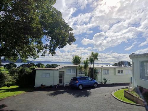 um carro estacionado em frente a uma casa em Adorable Beach Unit Stanmore Bay em Whangaparaoa