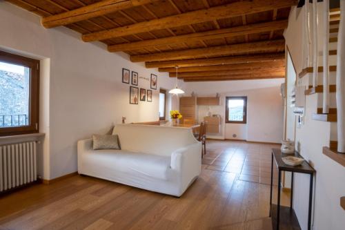 a living room with a white couch and wooden ceilings at Casa Pastello in Valpolicella in Cavalo