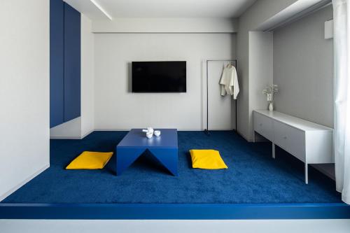 a room with a blue carpet and a table and a tv at Section L Tsukiji in Tokyo