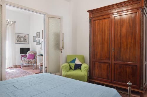 a bedroom with a bed and a green chair at Casina di Marnie in Balestrate