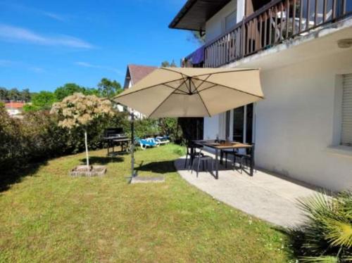a patio with a table and an umbrella next to a building at L'Ocenoa2 in Mimizan