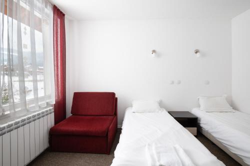 a room with two beds and a red chair at Atanasovata Kashta in Govedartsi