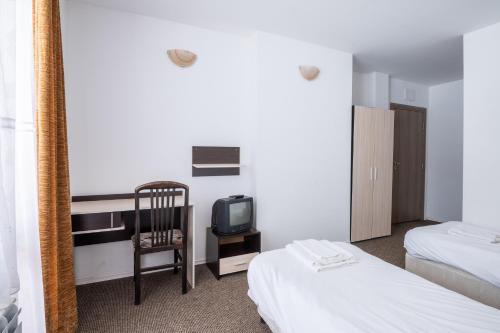 a room with two beds and a desk with a tv at Atanasovata Kashta in Govedartsi