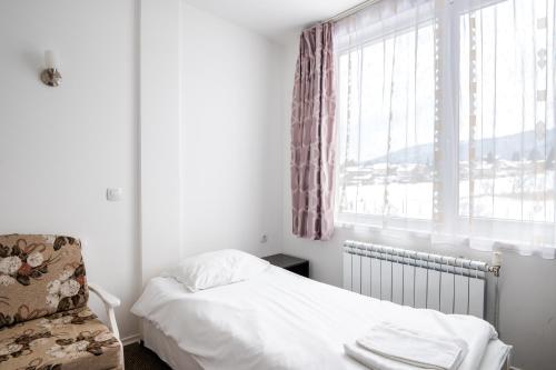 a bedroom with a bed and a chair and a window at Atanasovata Kashta in Govedartsi