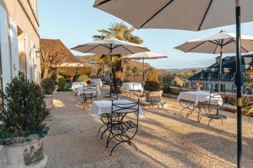 a group of tables and chairs with umbrellas at Hôtel l'Abbaye in Saint-Cyprien