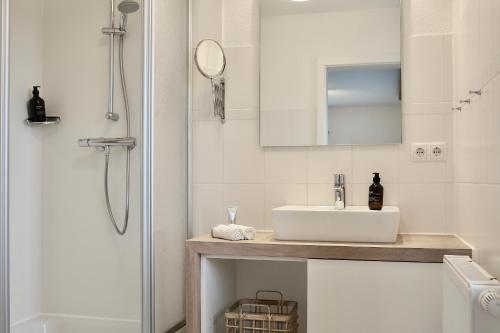 a white bathroom with a sink and a shower at Bauernhof Wulff - Fewo "Amrum" in Reußenköge