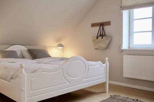 a white bed in a white bedroom with a window at Bauernhof Wulff - Fewo "Amrum" in Reußenköge