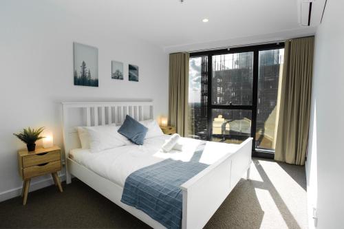 a bedroom with a white bed and a large window at Panorama Apartment Walk to Box Hill Central by GoodLive in Box Hill