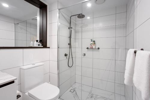 a white bathroom with a shower and a toilet at Panorama Apartment Walk to Box Hill Central by GoodLive in Box Hill