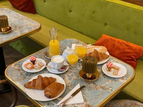 a table topped with plates of croissants and orange juice at Maison Kammerzell - Hotel & Restaurant in Strasbourg