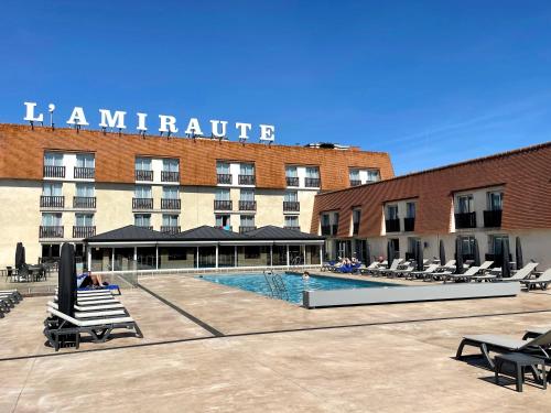 een hotel met een zwembad voor een gebouw bij Amirauté Hôtel Golf Deauville in Deauville