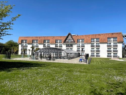 um edifício com uma estufa de vidro em frente em Amirauté Hôtel Golf Deauville em Deauville