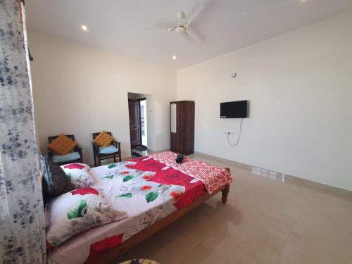 a bedroom with a bed and a flat screen tv at Fourseason frankcottage in Chikmagalūr