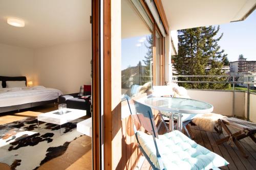 a room with a balcony with a table and a bed at Fortuna 1 in Arosa