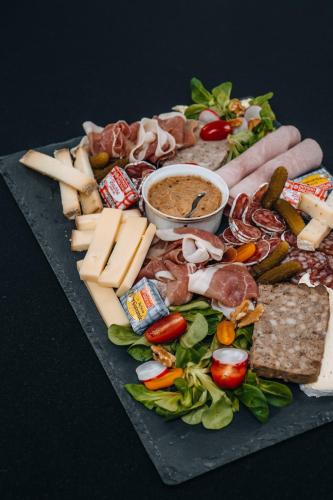 a plate of food with cheese and meats and vegetables at Hôtel l'Abbaye in Saint-Cyprien