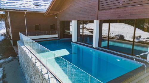 a swimming pool in a house with glass windows at TERRESENS - Les Roches Blanches in Combloux