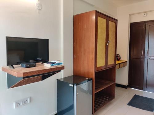 a living room with a television and a wooden cabinet at Olive Zip Calangute Mira by Embassy Group in Calangute