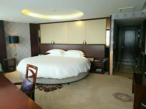 een slaapkamer met een groot bed met witte lakens en kussens bij Hengna International Hotel in Yiwu