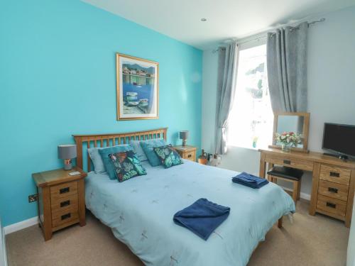 a bedroom with a large bed with blue walls at 4 Old Mill Court in Brixham