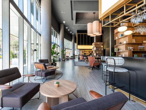 a lobby with chairs and tables in a building at Hotel Barcelona Condal Mar Affiliated by Meliá in Barcelona