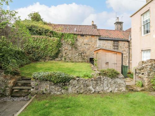 an old stone house with a stone wall at Dunira in Cupar