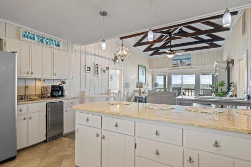 a large kitchen with white cabinets and a large island at The Beachcomber home in Pine Knoll Shores