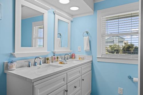 a bathroom with two sinks and blue walls at The Beachcomber home in Pine Knoll Shores